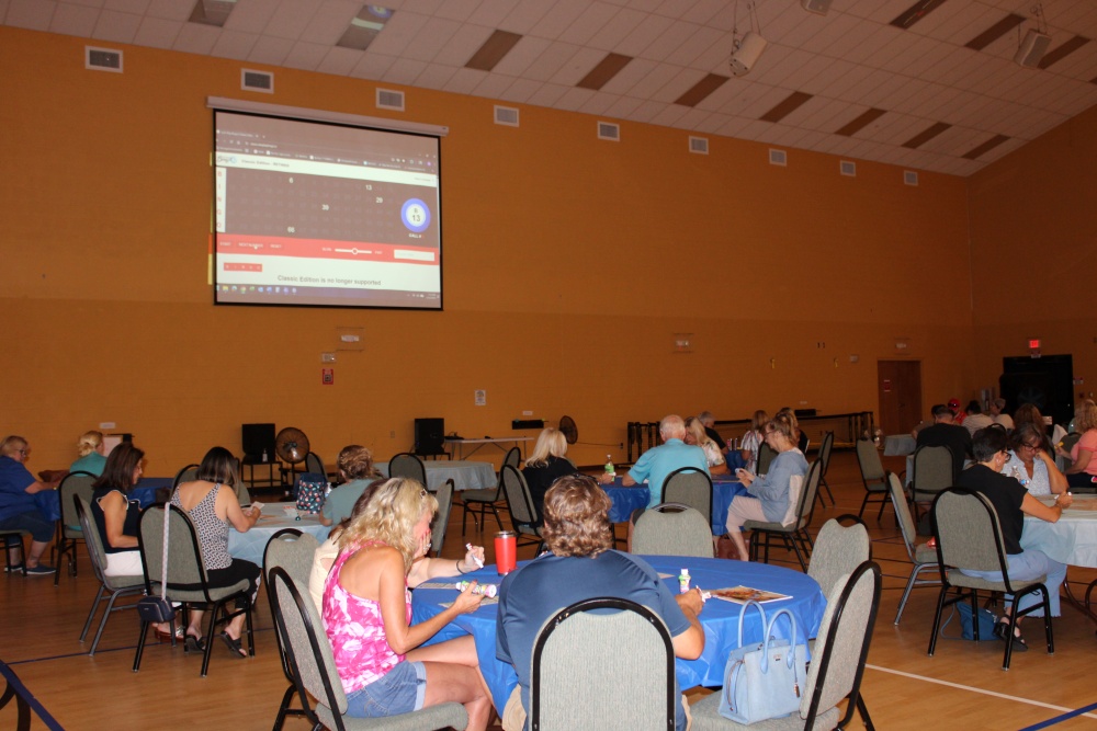 Group of older adults smile around a round table covered with bingo cards